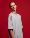Person wearing a light gray t-shirt against a red background