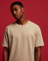 Man wearing a beige t-shirt against a red background