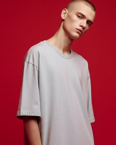 Person wearing a light gray t-shirt against a red background