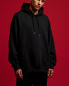 Person wearing a black hoodie against a red background